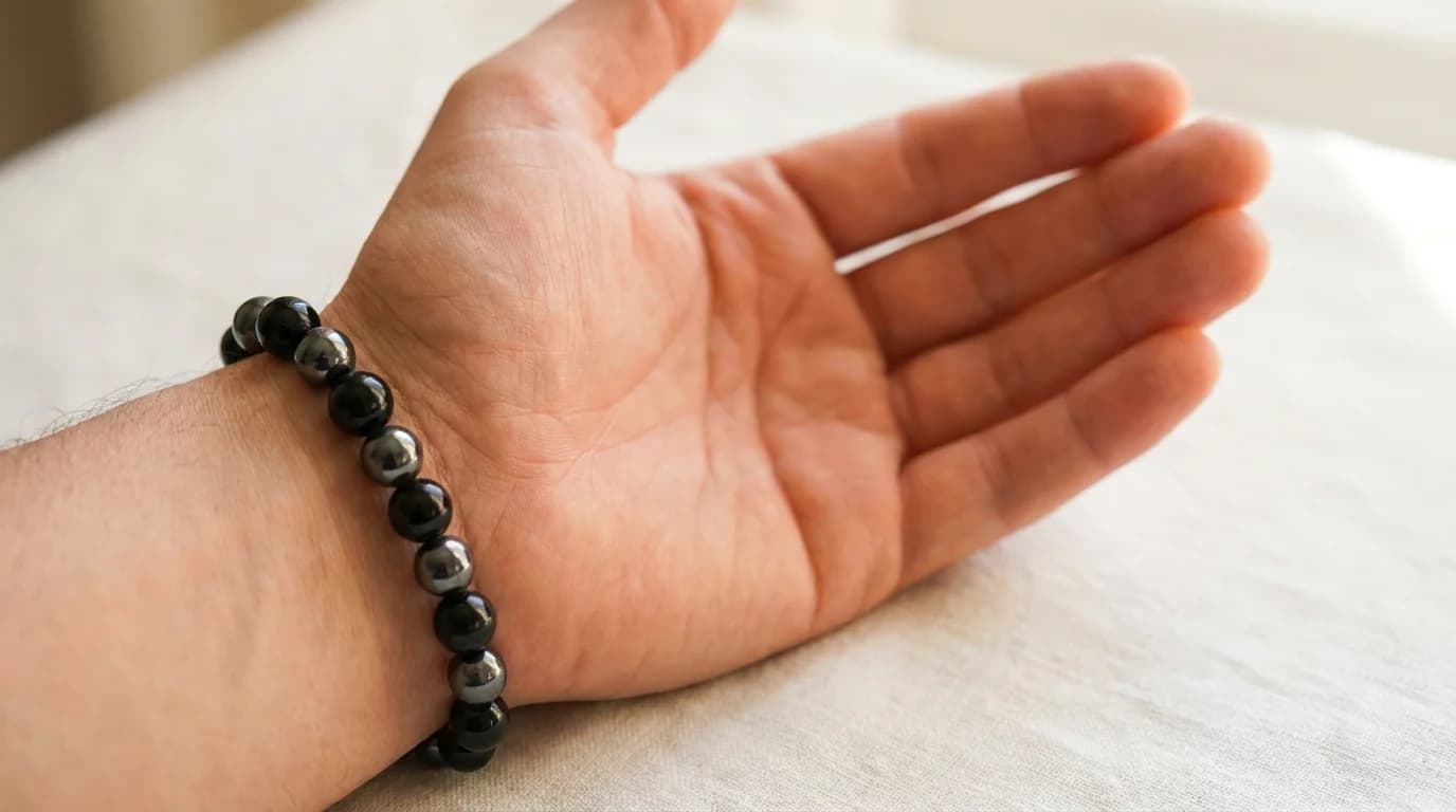 Black obsidian bracelet with hematite beads worn on the left wrist, with a lab certificate card