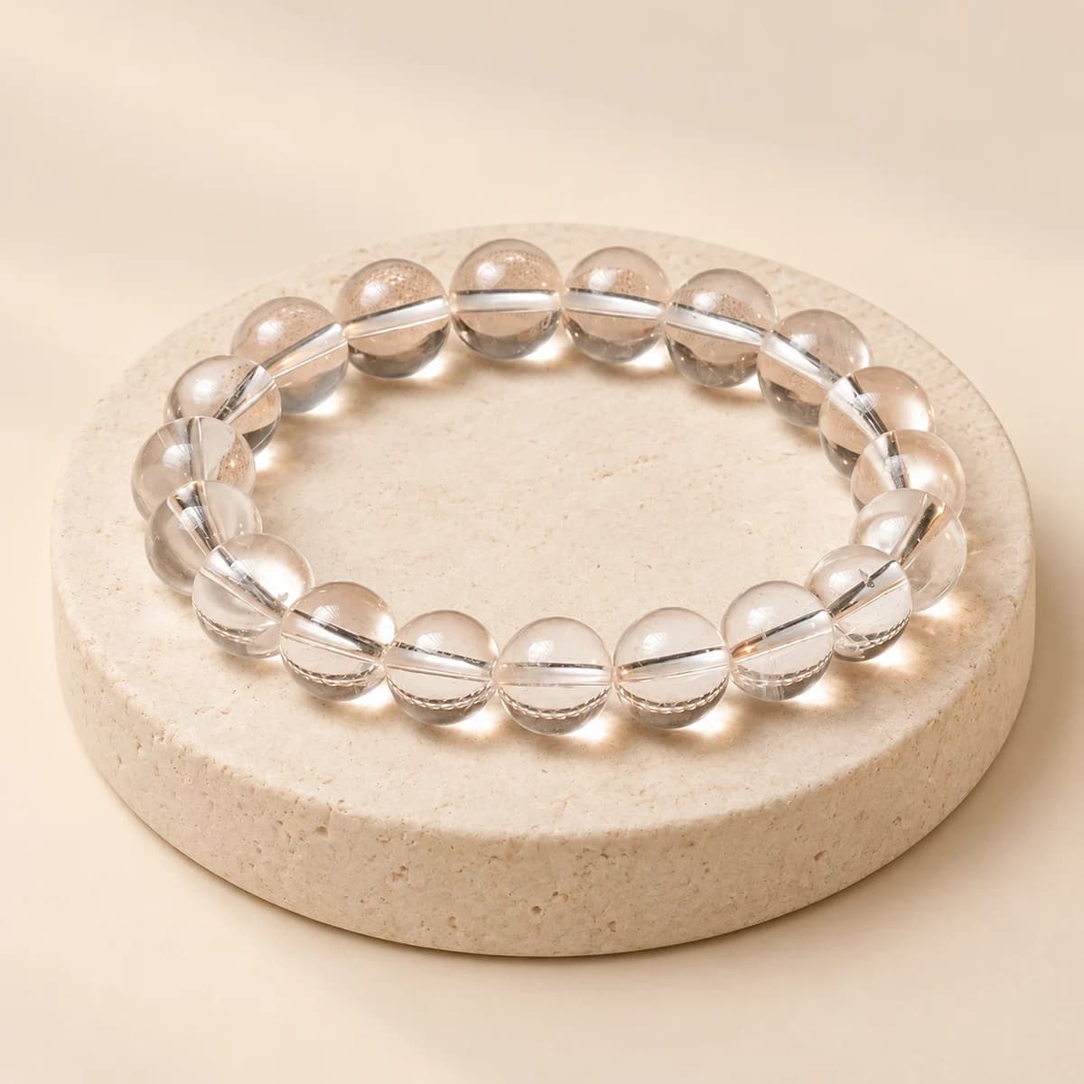 A bead bracelet of clear quartz, 8 mm polished transparent beads, on a light stone pedestal