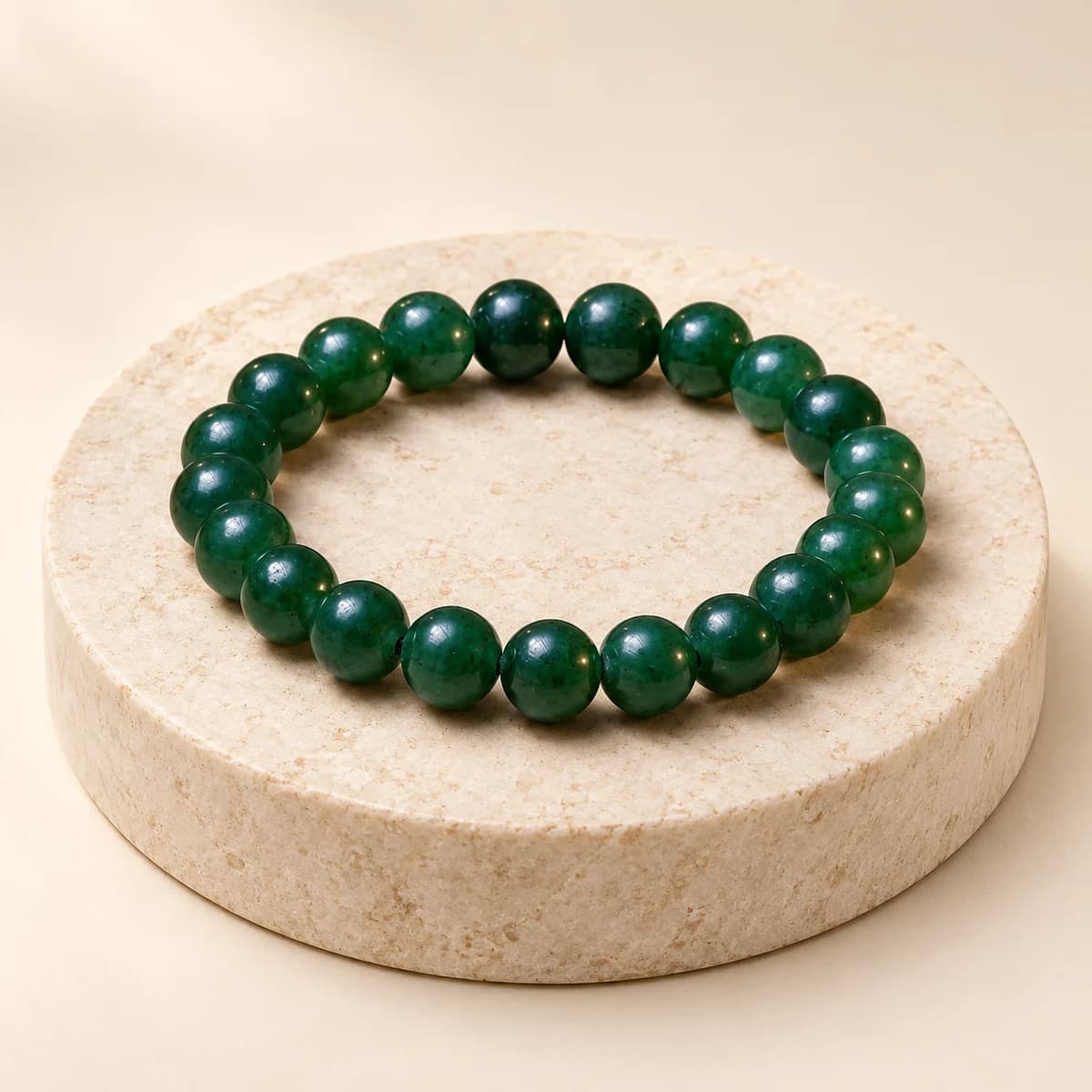 A bead bracelet of jade, 8 mm polished green beads, on a light stone pedestal