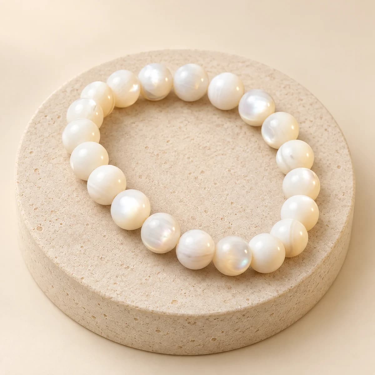 Lustrous 8 mm mother of pearl bead bracelet from DivineTatva on a light stone pedestal