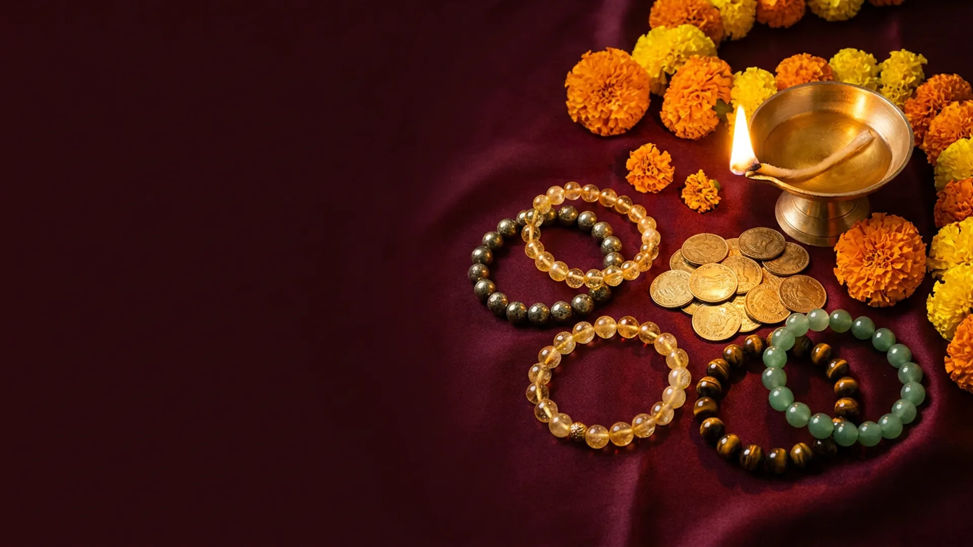 Money magnet crystal bracelets with gold coins, a brass diya and marigolds